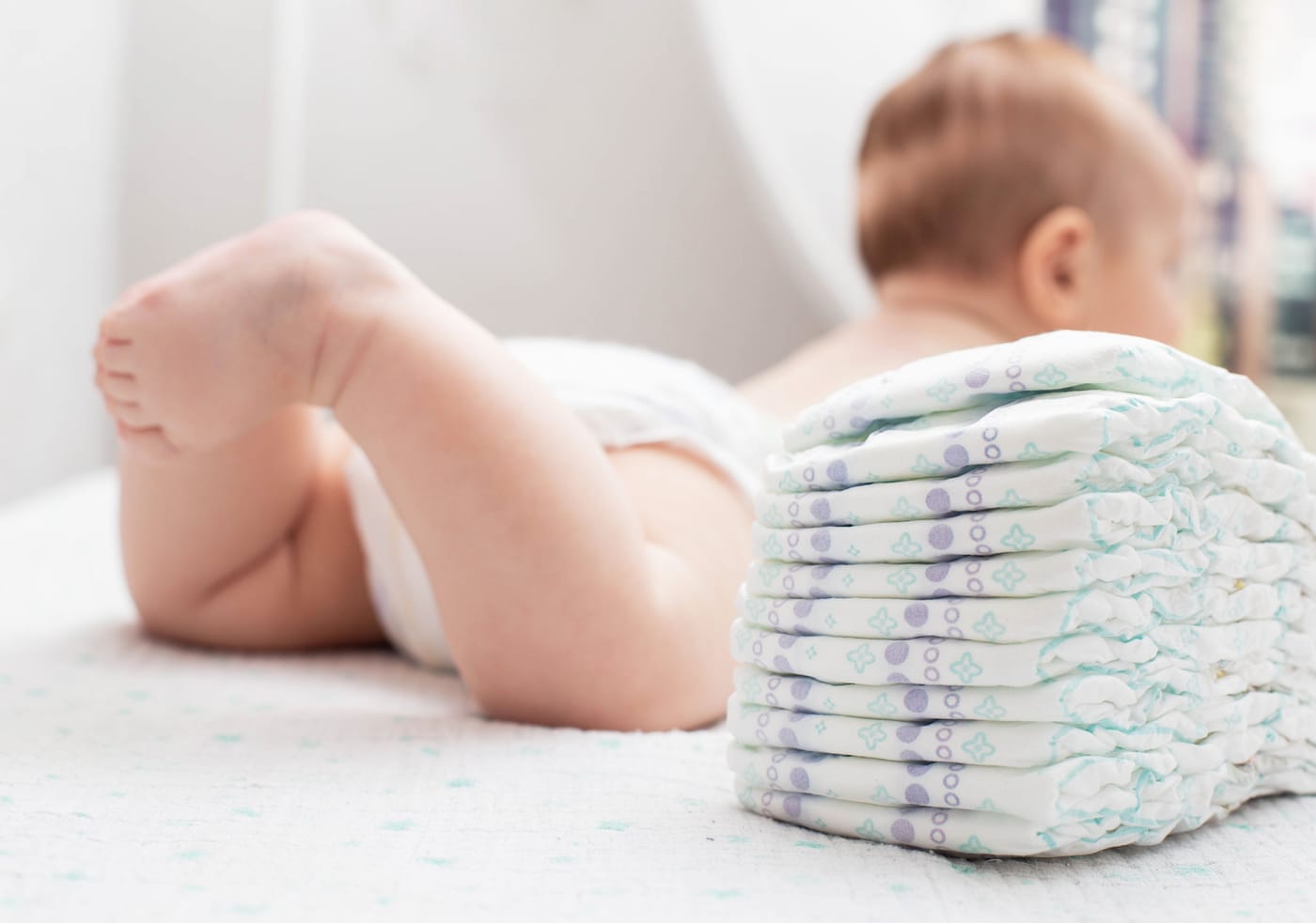 Newborn baby surrounded by diapers representing California's new Golden State Start diaper program
