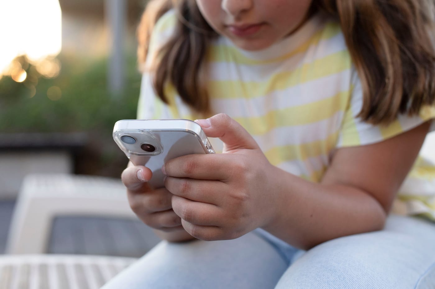 Teenagers looking at a phone outside representing the UK government announcement banning under-16s from TikTok Instagram Snapchat YouTube and Facebook starting spring 2027